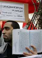 An Iranian man holds a copy of the Koran during a demonstration in front of the Austrian embassy in Tehran February 6, 2006. A crowd of about 200 people pelted the Austrian Embassy in Tehran with petrol bombs and stones on Monday in a protest over the publication of cartoons depicting the Prophet Mohammad.       