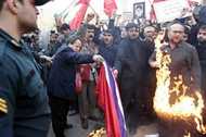 Iranian men burn flags and shout slogans during a demonstration in front of the Austrian embassy in Tehran February 6, 2006. A crowd of about 200 people pelted the Austrian Embassy in Tehran with petrol bombs and stones on Monday in a protest over the publication of cartoons depicting the Prophet Mohammad.     